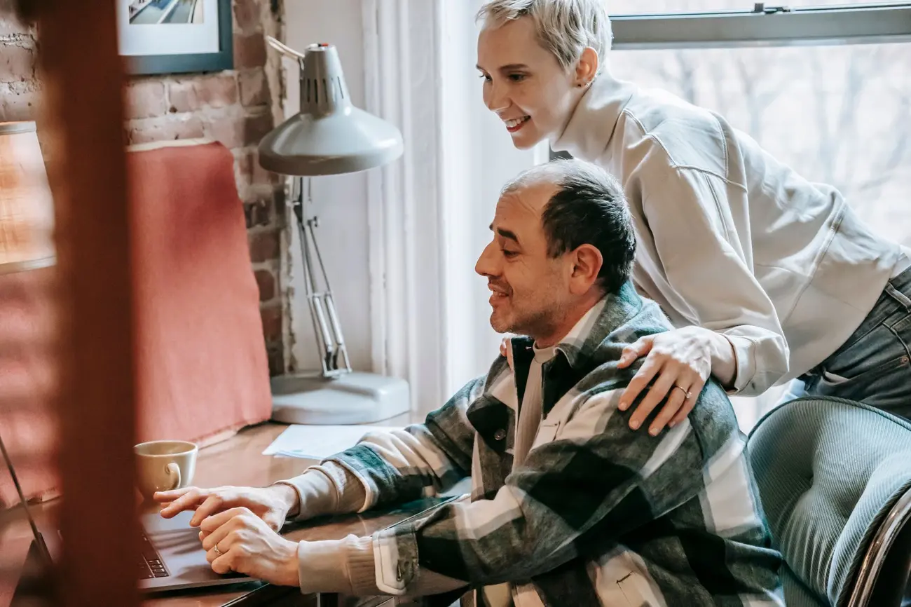 A couple organising their partner visa evidence on a laptop